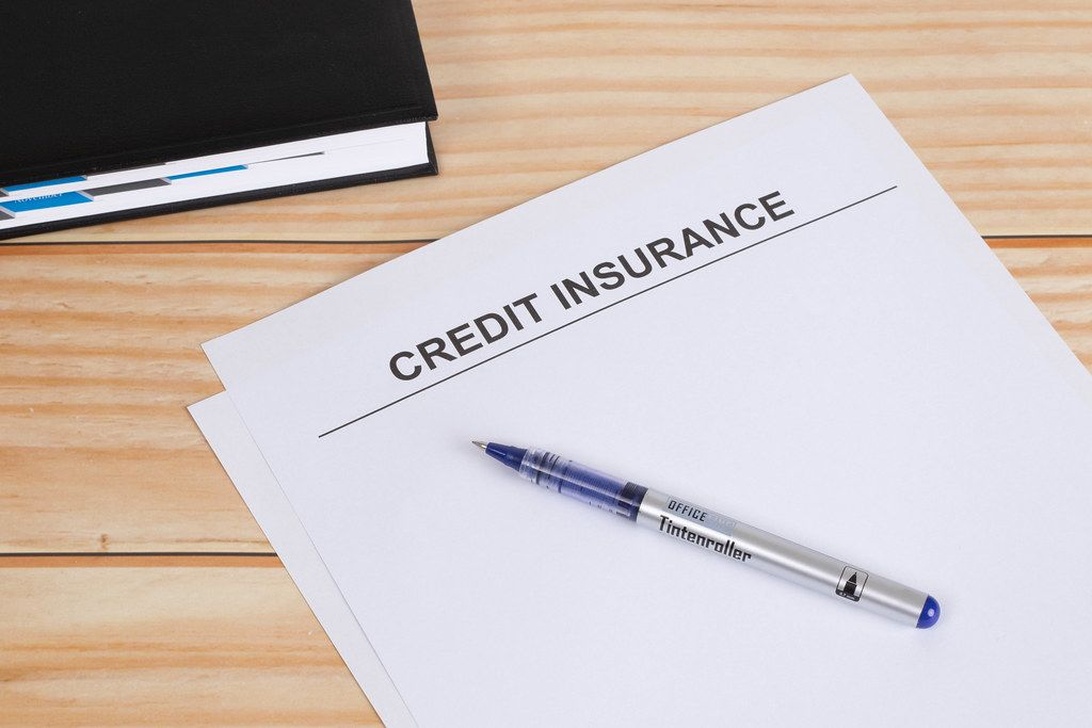 Asiakirja otsikolla 'CREDIT INSURANCE' ja sen päällä sininen kynä puisella pöydällä.